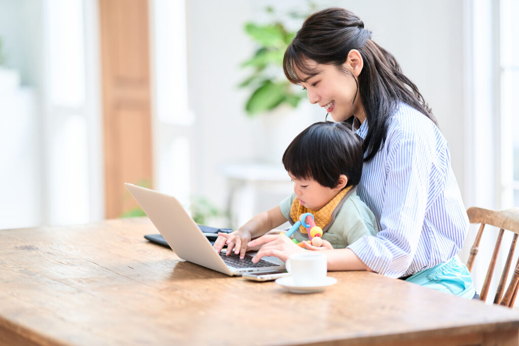 子どもを育てながらパソコンに向かう女性