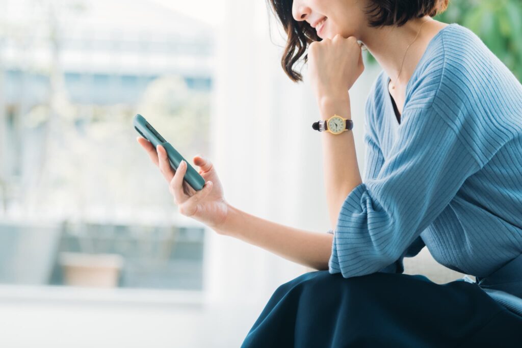 スマホを手に微笑む女性